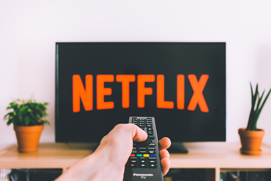 Remote control pointing to screen showing Netflix
