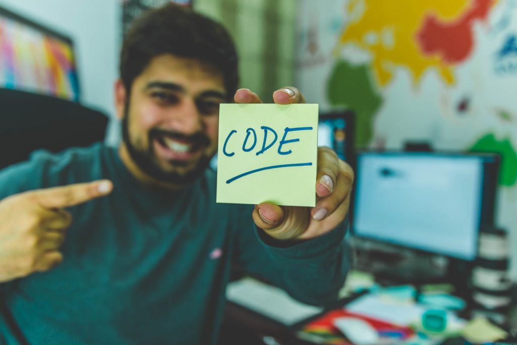 Man Holding a Post it saying Code