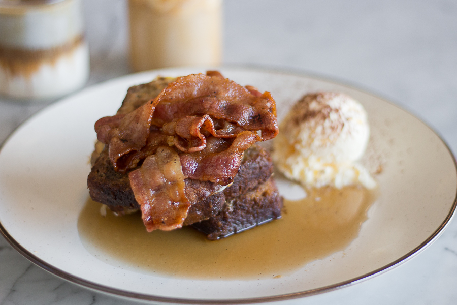 A plate of banana bread french toast with bacon and vanilla ice cream