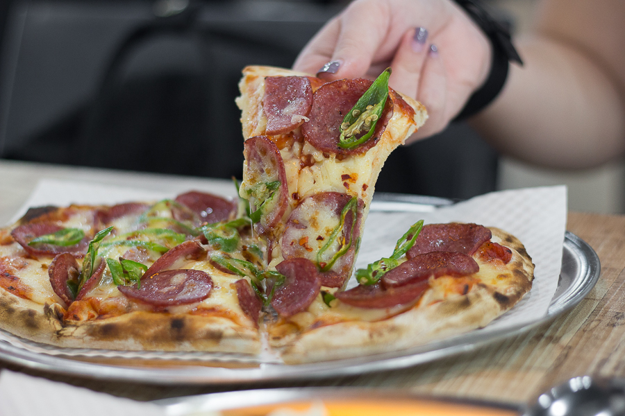 Someone pulling a slice of Cheongyang Pepperoni Pizza at GoPizza Singapore