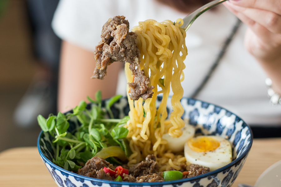 Someone holding a fork taking a portion of bulgogi ramyeon from Kong Cafe