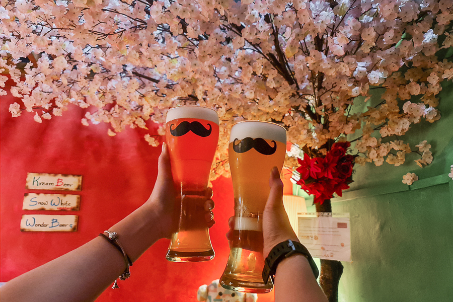 Someone Holding Beer Glasses with Moustache Design With Cherry Blossoms Interior at Kreams Beer