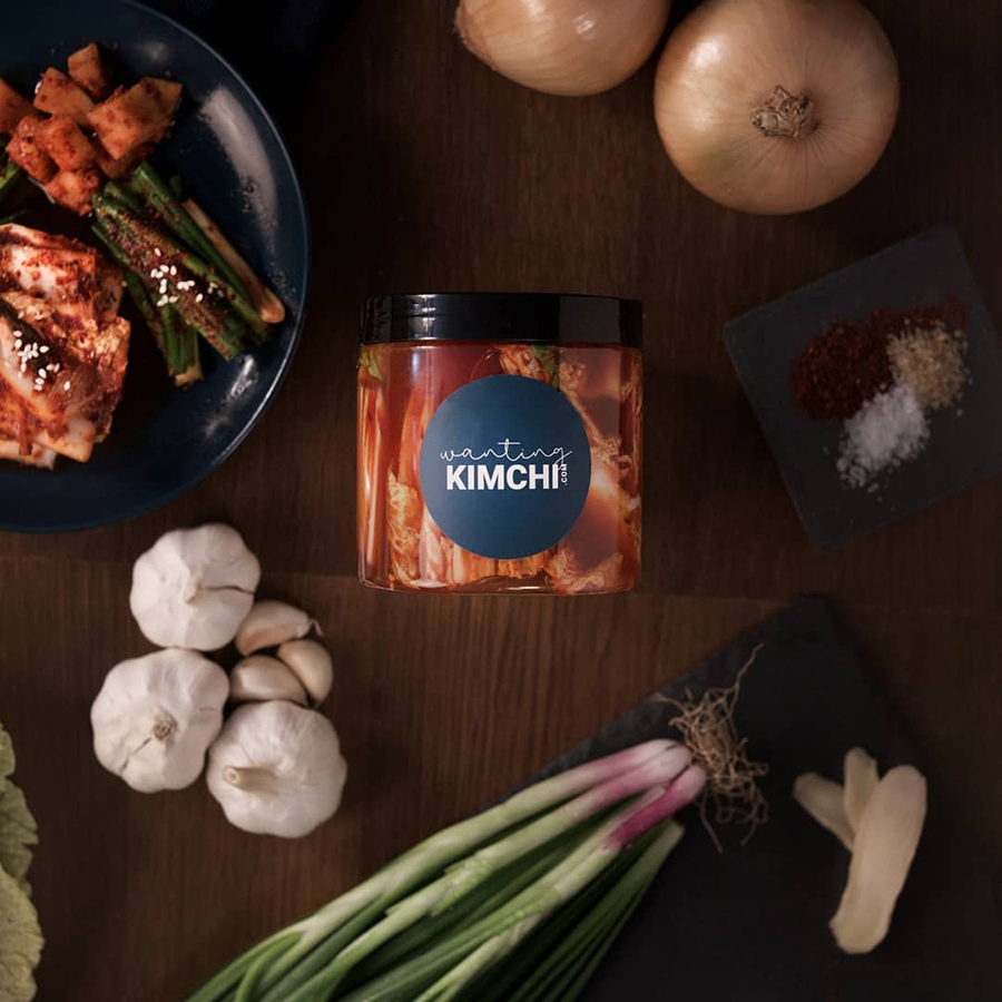 A tub of kimchi surrounded by ingredients used in making the kimchi
