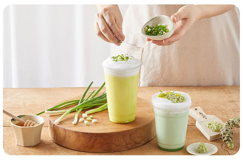 someone topping off a green onion latte with freshly cut green onions