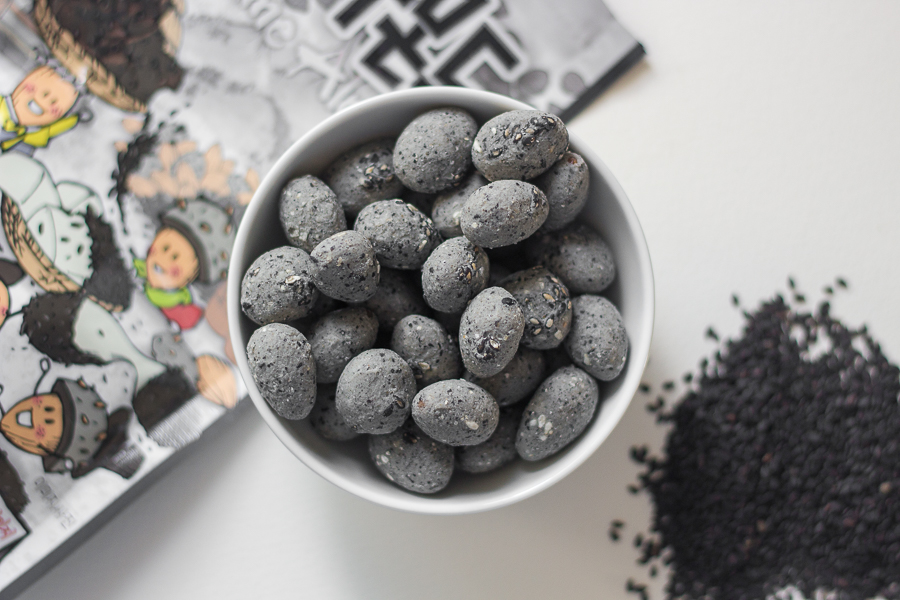 HBAF Black Sesame Almonds in a white ceramic bowl with black sesame at the bottom right corner