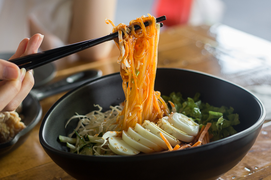 A pair of chopsticks holding up some Jjolmyeon (Korean cold chewy noodles) at Ahtti Jurong East
