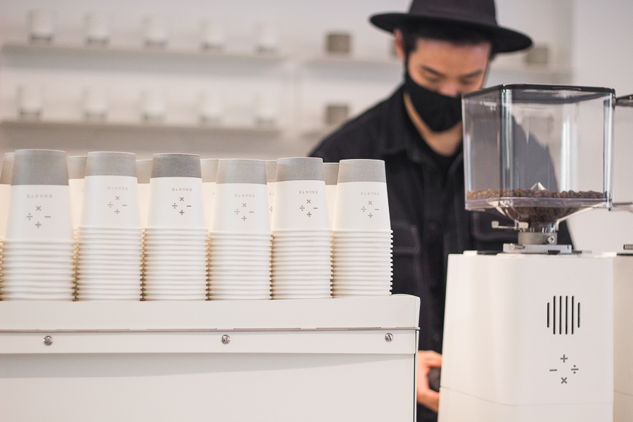 Rows of paper cups with equate coffee's logo on it placed on top of an espresso machine