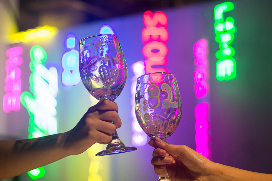 Self decorated wine glasses with neon signs at the back