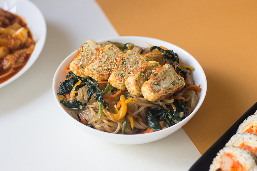 A bowl of Japchae with egg roll on top