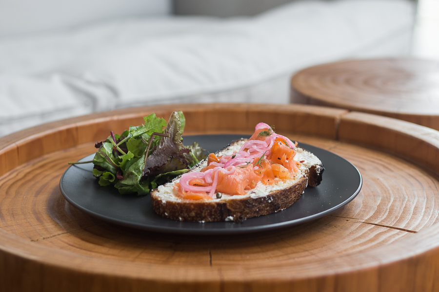 A plate of salmon and ricotta tartine with house salad served on the side