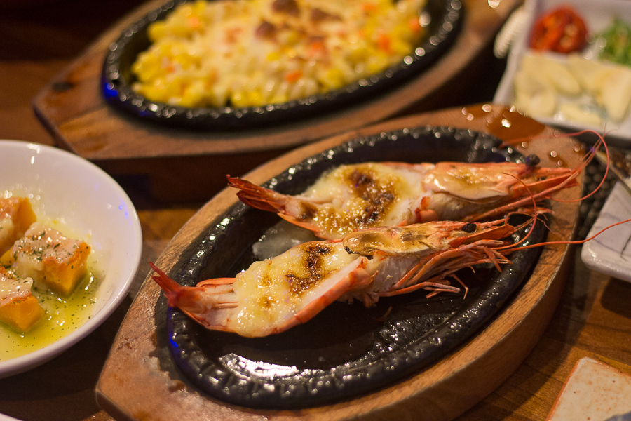 Two pieces of grilled prawns topped with cheese and condensed milk