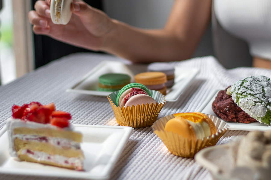 Someone holding a macaron at a table of Korean inspired desserts