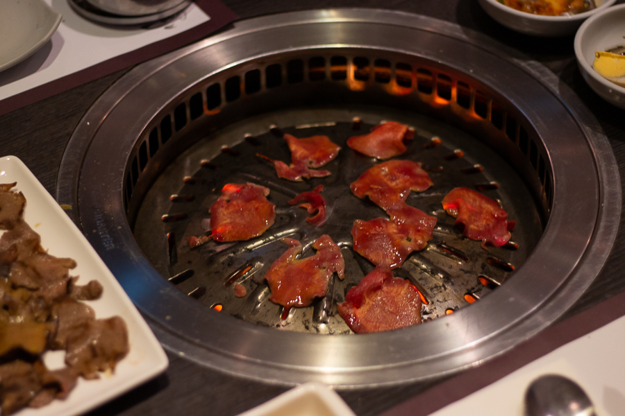 beef tongue grilling on top of a charcoal fire