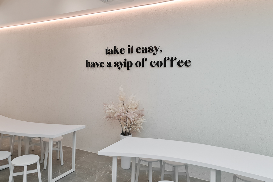 Wall with words saying "Take it easy, have a SYIP of coffee"