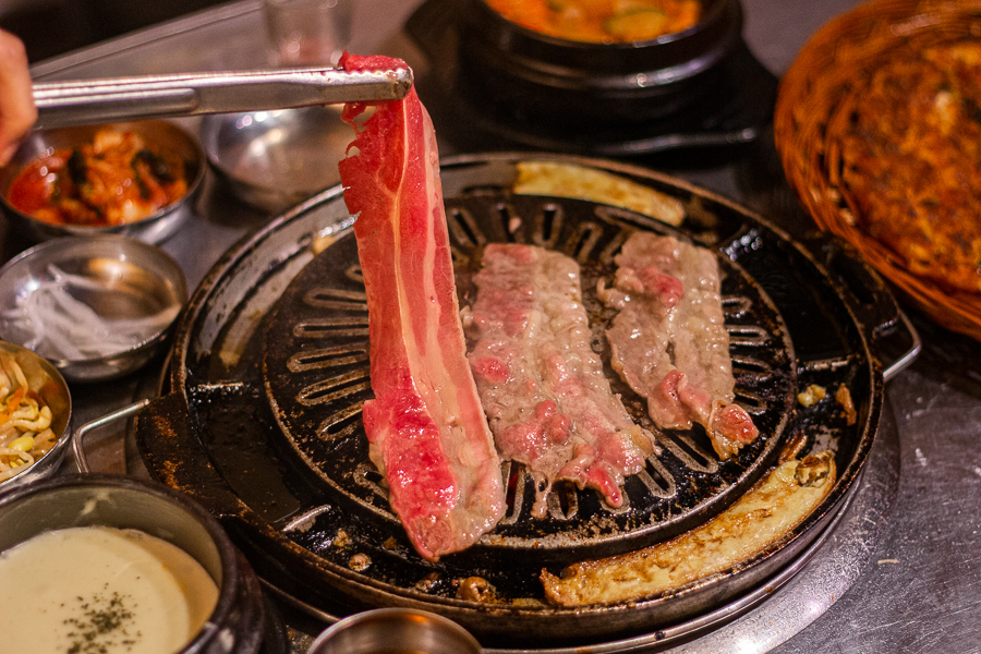 Grilling slices of beef brisket on charcoal bbq at Wang Dae Bak