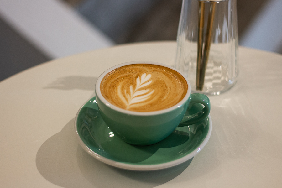 A Cup of Flat White in a green coloured cup