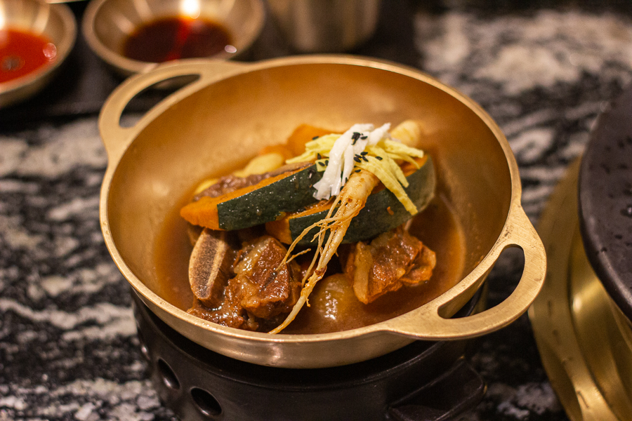 A bowl of Galbijjim in Bronzeware served together pumpkin slices and ginseng