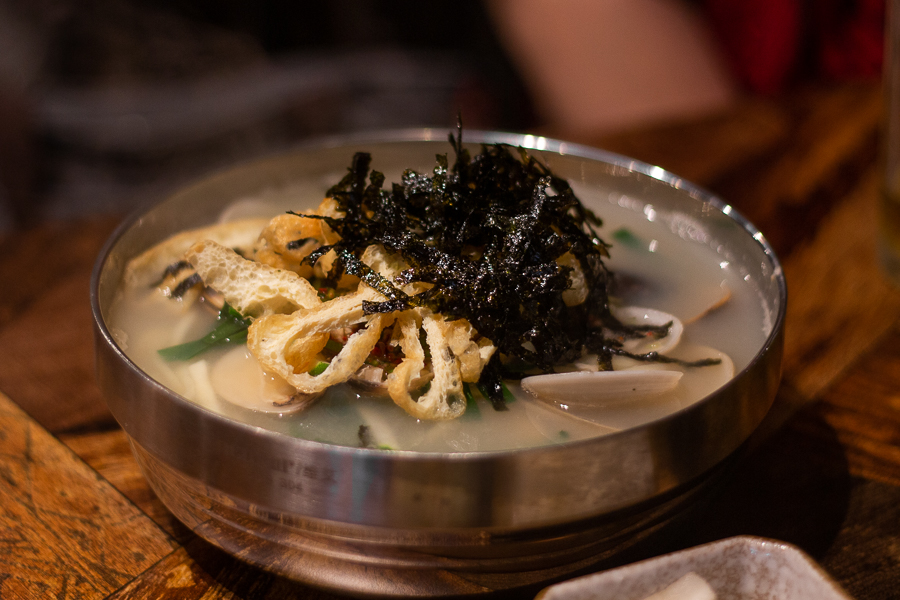 A bowl of Clam Kalguksu topped with seaweed and dried beancurd skin