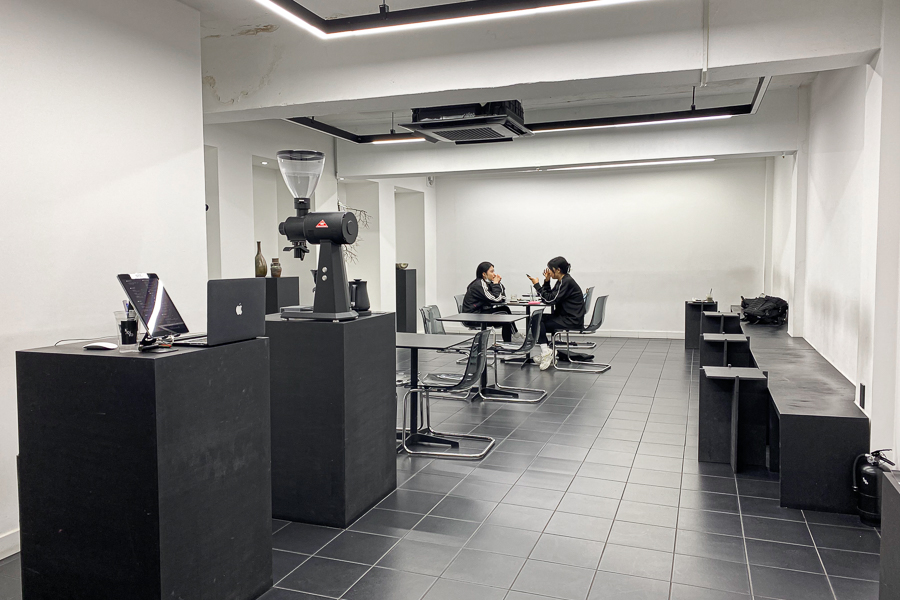 Interior of a Seongsu cafe filled with black chairs and black tables with white walls