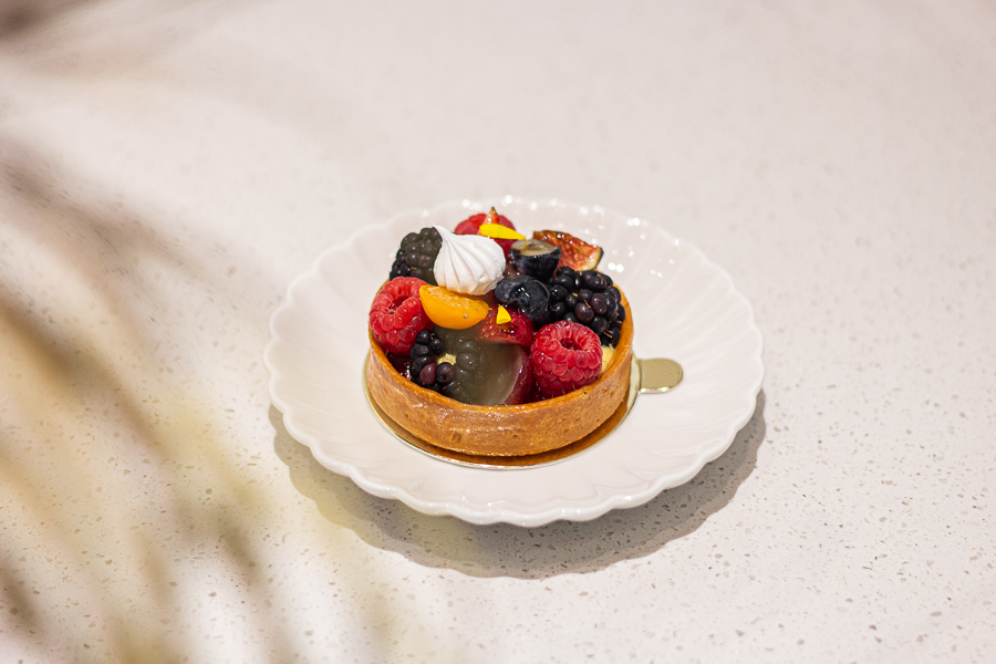 A tart topped with mixed berries such as blackberries, raspberries, fig and strawberries