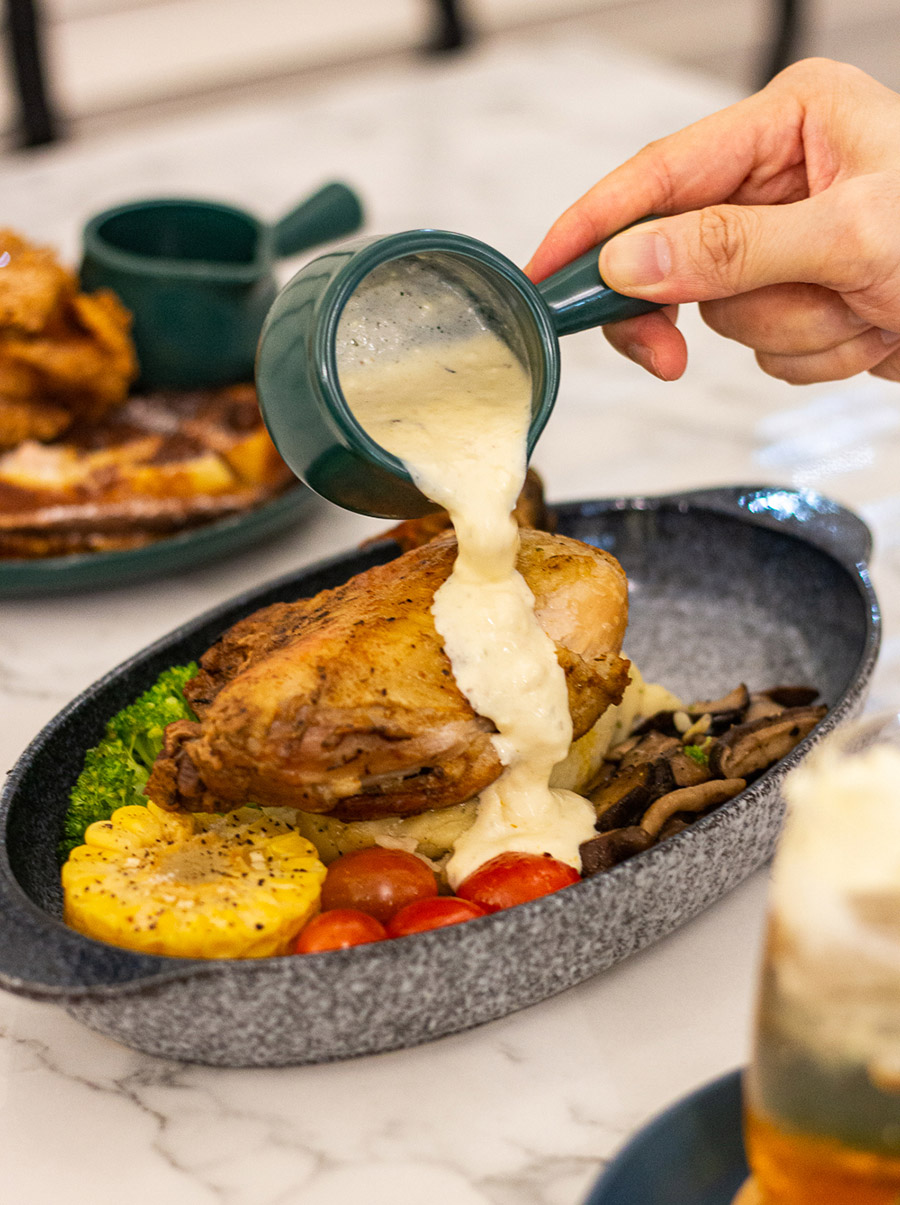 Pouring Cream sauce onto a grilled free-range chicken