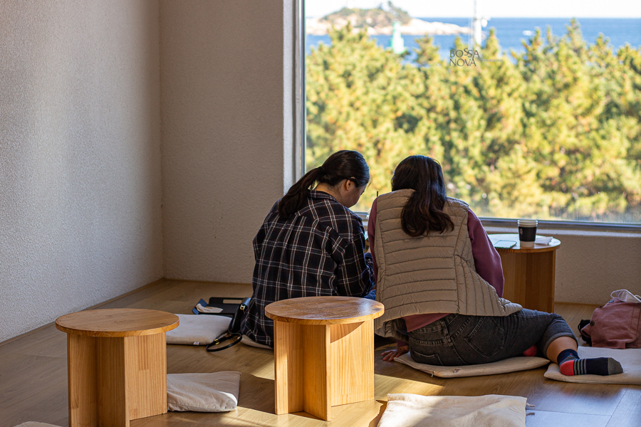 2 girls sitting facing pine trees and the ocean at bossa nova cafe sokcho