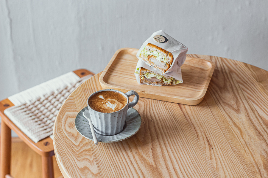 A Cup of Flat White and Chicken Katsu Sando on a table