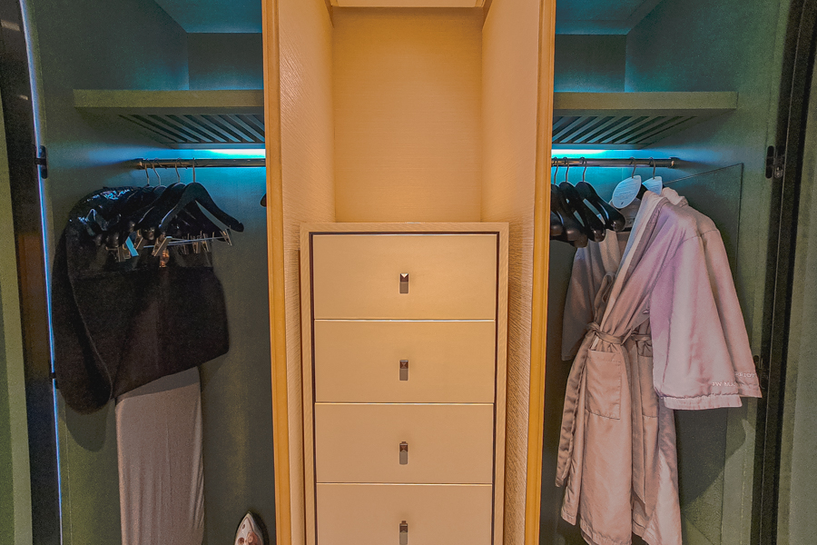 Hotel closet with bathroom robes, hangers, ironing board and iron