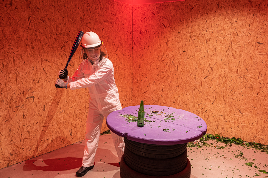A man suited up in full protective gear to smash a glass bottle in the Smash Lab