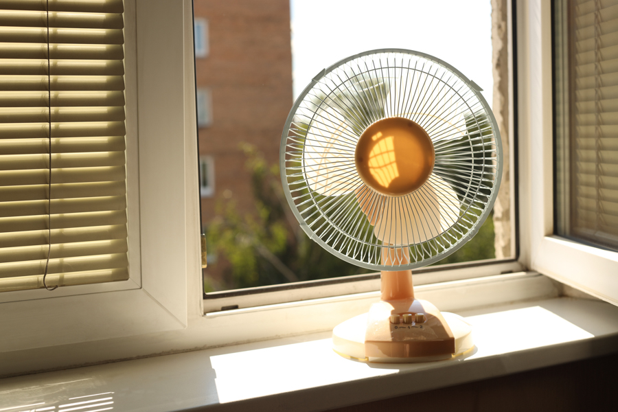 An electric fan on the windowsill of an open window