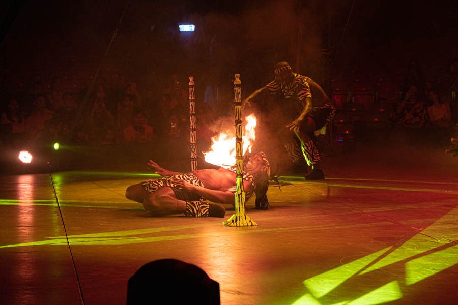 A performer doing limbo under a flaming stick