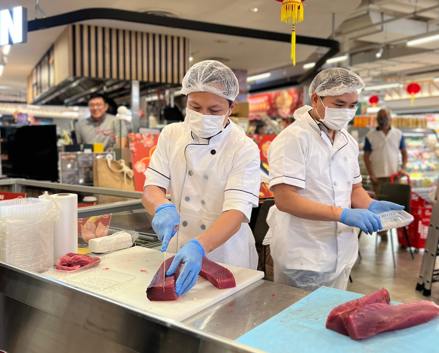 Chefs slicing fresh tuna sashimi at FairPrice XTRA