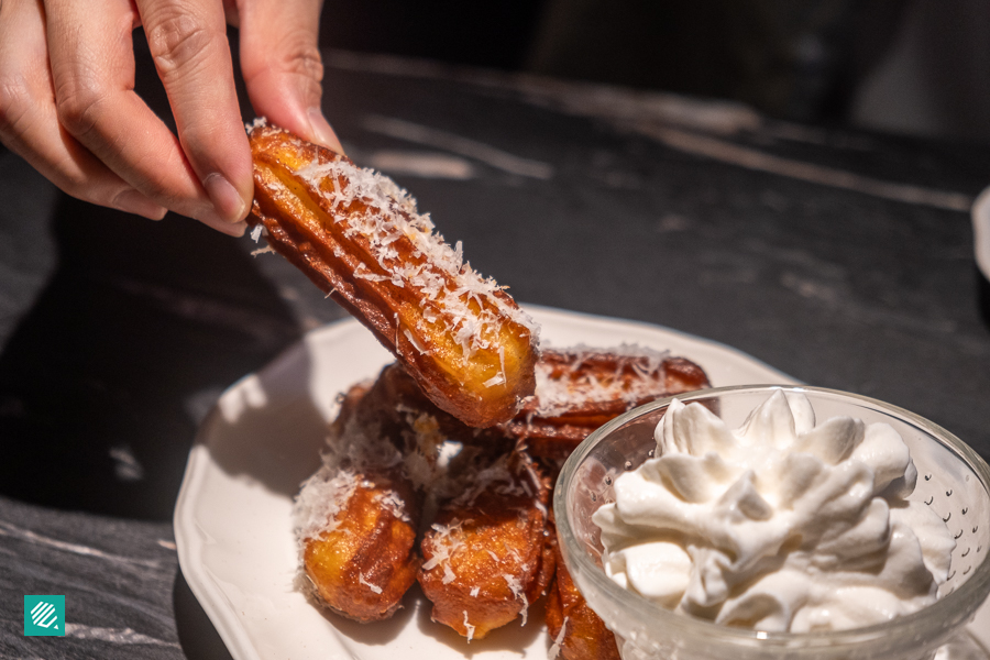 A person holding a piece of Parmesan Churros