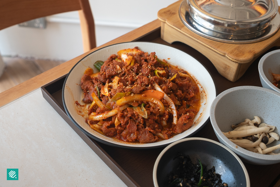 A plate of Korean stir-fried pork surrounded by rice and side dishes